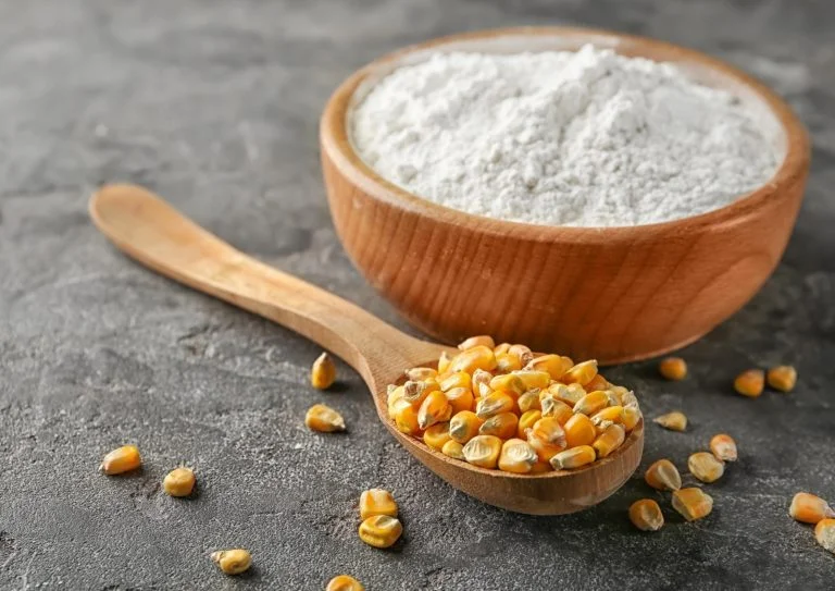 corn on the spoon and powder in the wooden cup